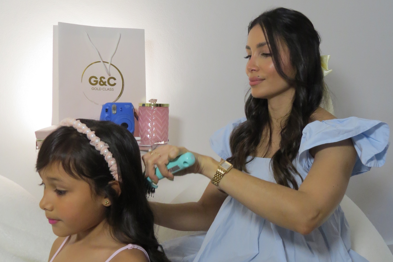 Woman styling a child's hair with a detangling brush g&c gold class