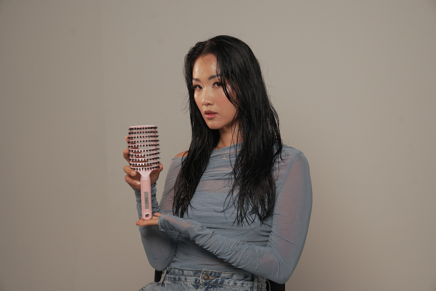 Woman holding a g&c detangling brush gold class