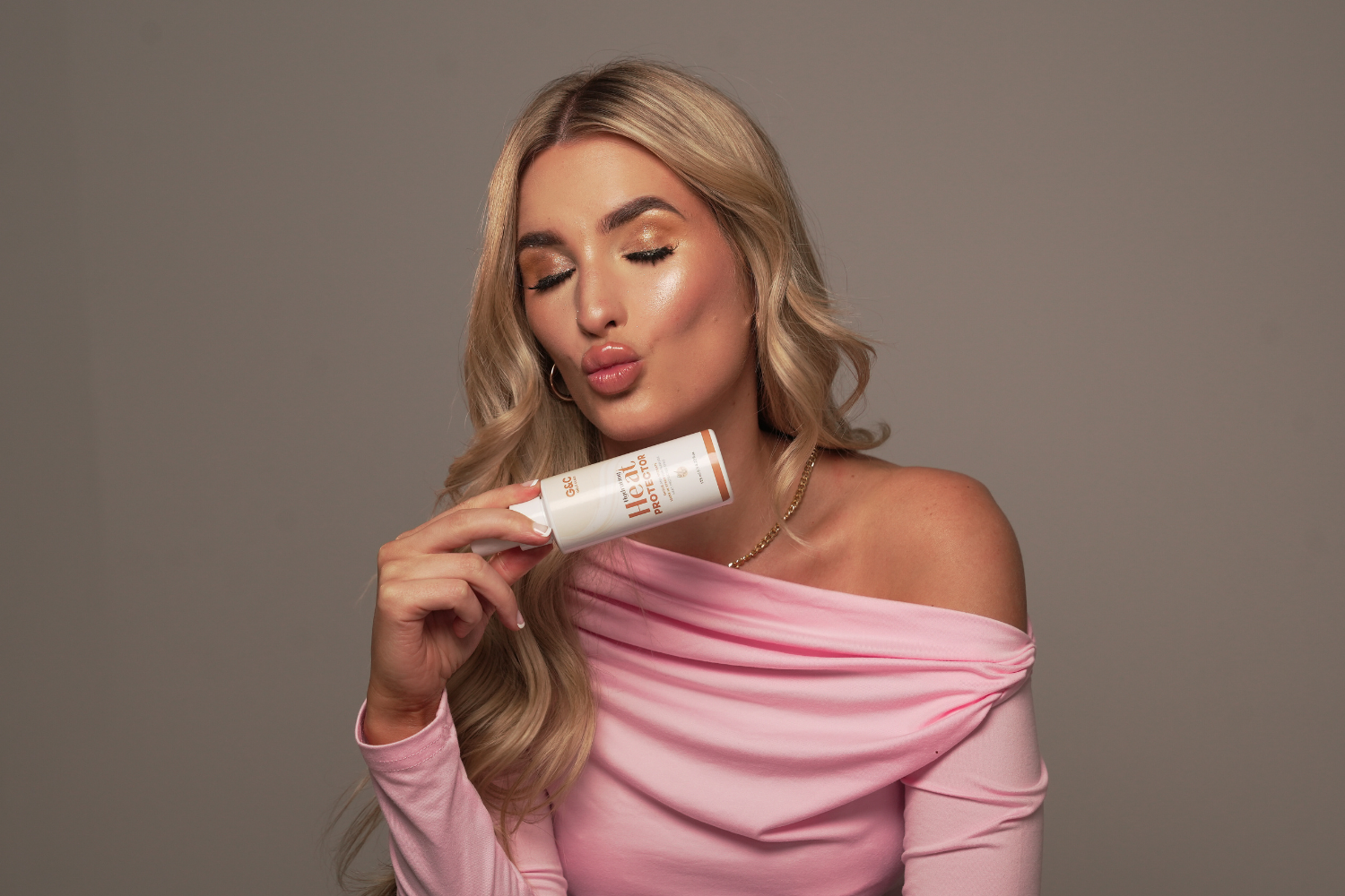 Woman holding a heat protectant vegan and organic gold class g&c
