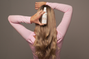 Woman holding a bottle of hair product with long blonde hair gold class g&c